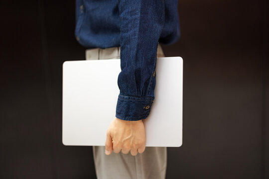 Person Holds Laptop While Standing in an Elevator
