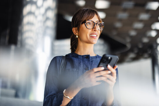 Woman Using Smartphone While Standing Outside of a Modern Building