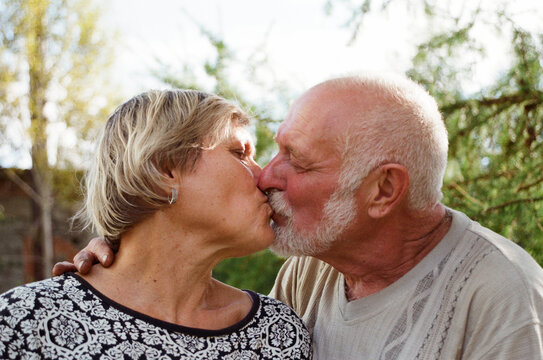 Couple sharing a kiss in a garden during sunset