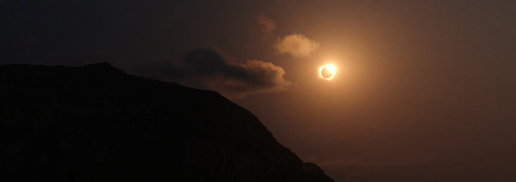 Annular solar eclipse creating diamond ring effect over mountain