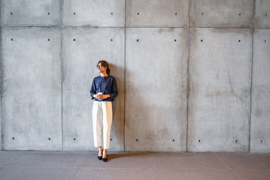 Woman Stands by a Concrete Wall in a Modern Building