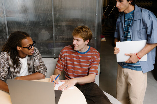Three creative people sharing ideas in a modern startup workspace.