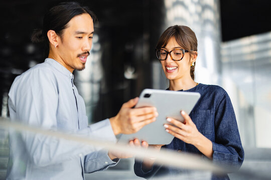 People Discussing Ideas While Looking at a Tablet in a Modern Space