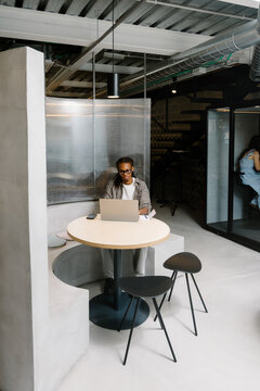 Creative Black man working on a laptop in a modern office common area
