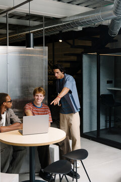 Business development team discussing a project around a laptop.