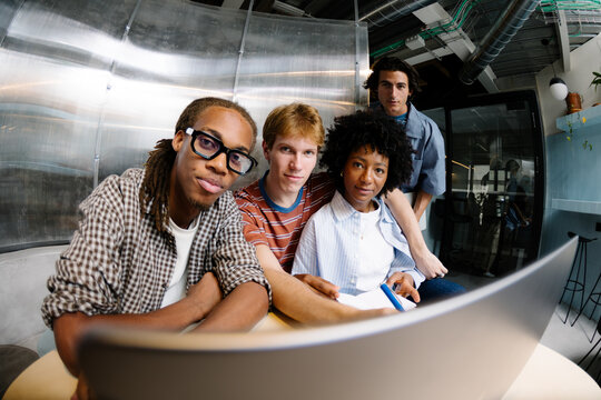Diverse startup founding team posing seriously at a shared desk.