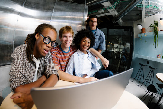 Young professionals using a laptop together at a shared desk.