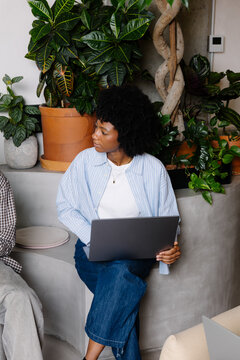 Woman in a red dress working on a laptop in a coworking space.