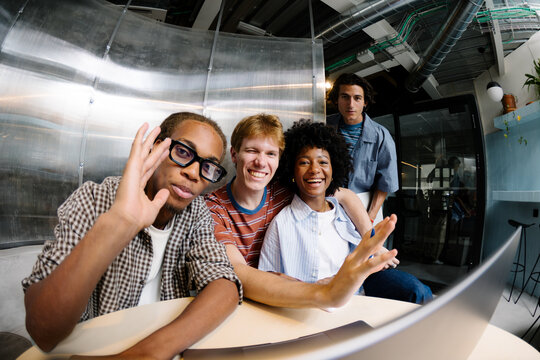 Small business team waving and smiling at a shared conference desk.
