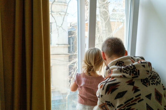Father and young child looking out the window together