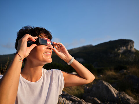 Woman observing solar eclipse using protective glasses outdoors