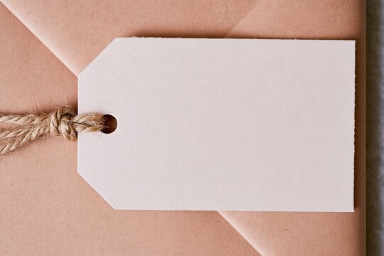 Blank gift tag with a jute twine knot on kraft paper wrapping, featuring a fibrous texture and copy space for a craft mockup