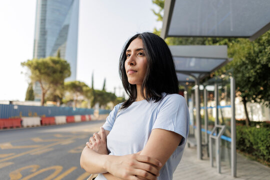 Young woman standing contemplating future at bus stop