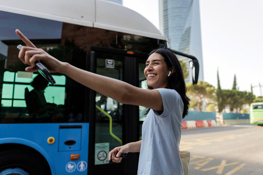 Young woman smiling hailing bus on city street