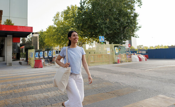 Young woman smiling walking across urban pedestrian crossing
