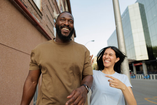 Diverse couple enjoying city walk, laughing together
