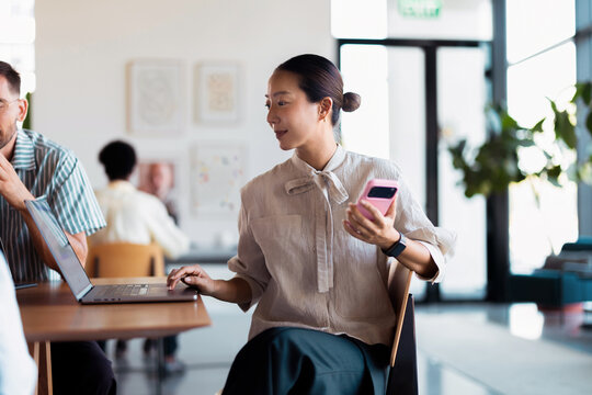 Businesswoman Working on Laptop and Smartphone in Modern Office