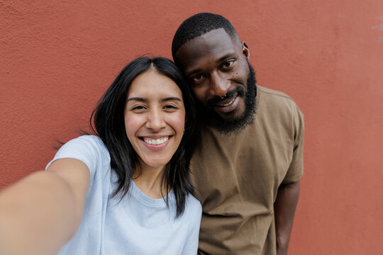 Diverse couple smiling taking a happy selfie