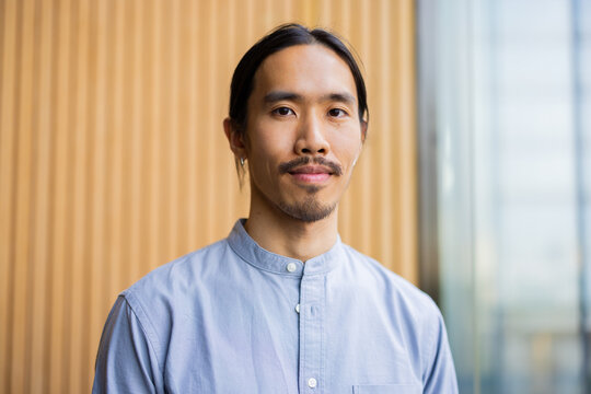 Man Poses Outdoors With Wooden Background