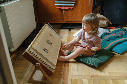 Young child sitting on the floor with a traditional stringed instrumen