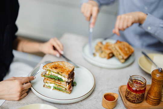 People Enjoying Sandwiches at a Table in a Cafe