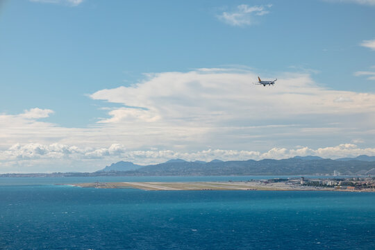 Airplane is descending over the mediterranean sea with the Nice Cote d'Azur airport runway and French Riviera coastline visible in the background, signifying travel and arrivals