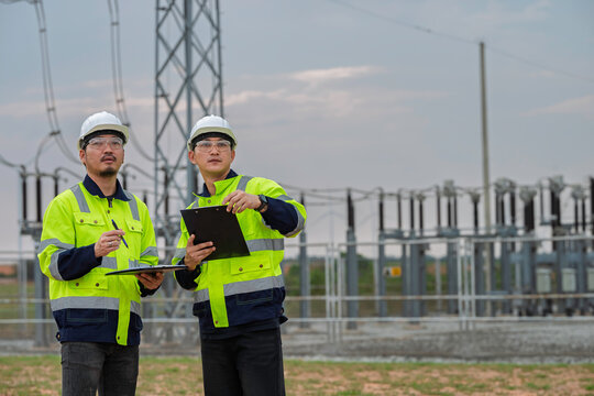 Electrical engineering team reviews high voltage substation infrastructure during routine inspection, representing power transmission, grid reliability, maintenance, and utility safety.