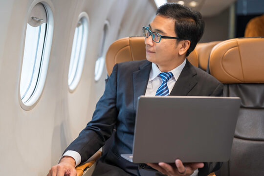 Asian businessman and business class flight. Asian business man in formal suit sitting in airplane during flight
