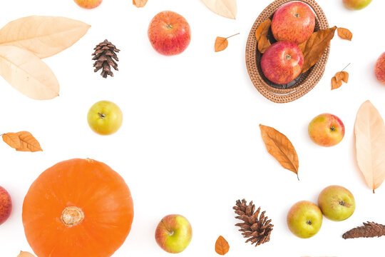 Pumpkin, apples, leaves and nuts arranged on white with generous copy space.