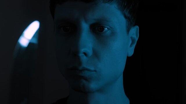 Man staring at a knife while struggling with suicidal thoughts and inner despair, showing emotional crisis and hopelessness in a dark blue cinematic home interior with dramatic lighting