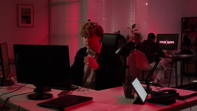 Caucasian young adult analyst typing on computer while Asian colleague assisting during cyber crisis. Footage serves IT security campaigns and software marketing
