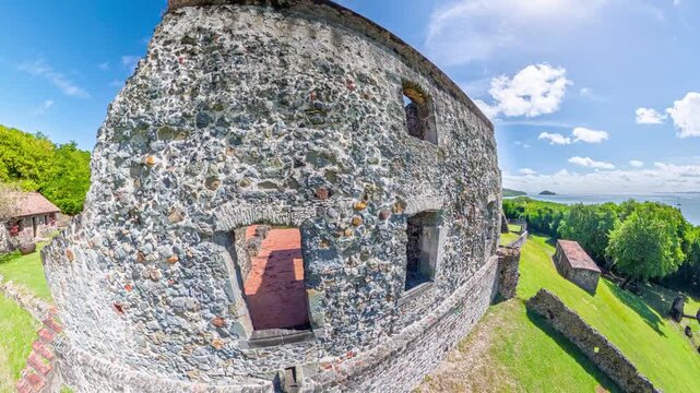 Chateau Dubuc, a historic colonial plantation ruin on the Caravelle Peninsula, showcases its ancient stone walls and remnants against a sunny sky and tranquil bay in Martinique, France