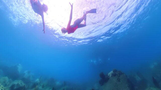 woman and man swimming over sunlit Caribbean reef, exploring clear blue tropical waters and rocky seabed in Martinique, enjoying vacation snorkeling and marine life views French Antilles in of France