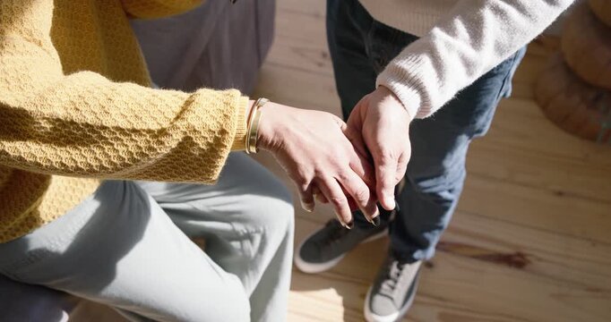Seated person extending hand, carer reaching, turning wrist, adjusting bangle for help near couch