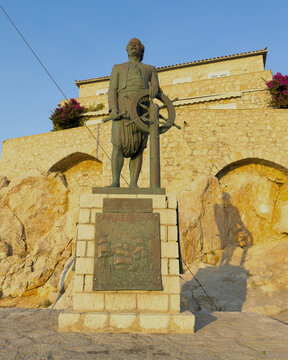 Bronze Andreas Miaoulis statue against stone architecture wall in Hydra, Greece