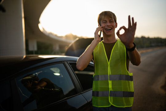 Young man calling for roadside assistance after car breakdown