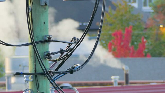Close Up of Electrical Cables on Utility Pole with Rooftop Steam Exhaust