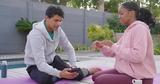 African American duo sitting on purple mats by pool, man showing cell, woman tapping, choosing plan