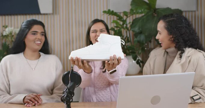 Diverse female hosts starting review center host turning white sneaker checking sole talking on mic