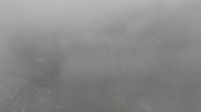 Aerial view of winding road through dense fog at Fluela Pass in Zernez, Grisons, Switzerland.