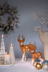 Christmas shelf decoration with deer figurines wreath baubles and silver candles on blue wall © PNG Creator
