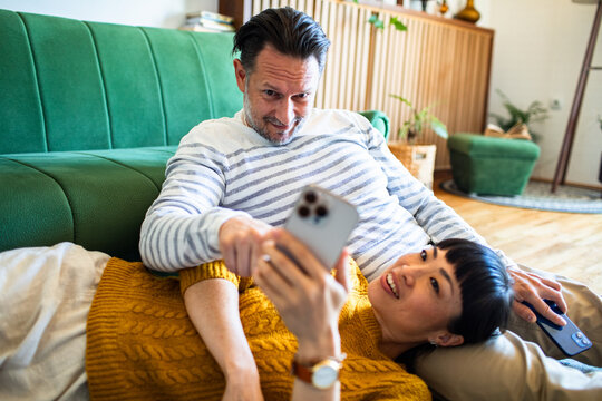 Couple relaxing at home looking at a smartphone
