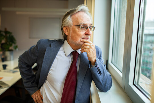 Senior businessman thinking by office window