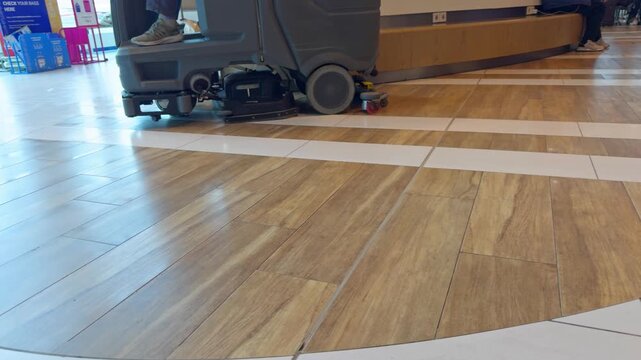 Industrial floor scrubber machine cleaning glossy modern tile and wood pattern floor interior