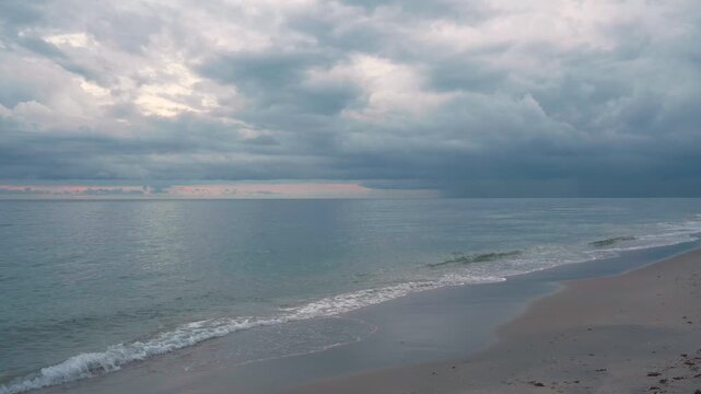 waves gently crashing on sandy beach with storm clouds over ocean