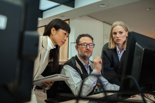 Man explaining computer screen to colleagues in office