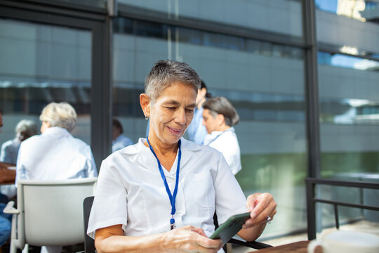 Smiling nurse using smartphone on hospital patio
