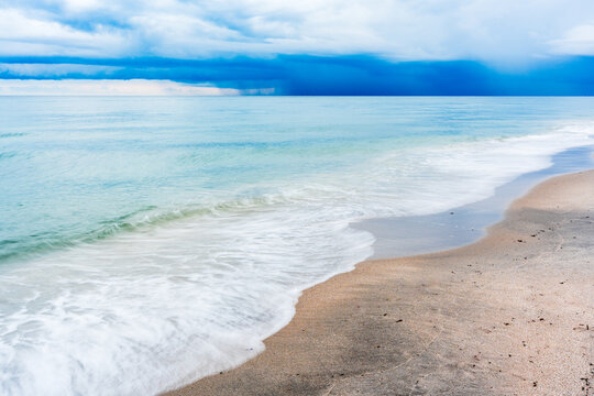 waves gently crashing on sandy beach with storm clouds over ocean