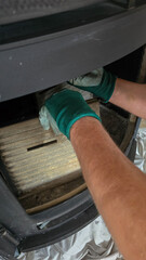 Naklejka premium Worker in protective green gloves assembling internal thermal insulation in wood burning stove.