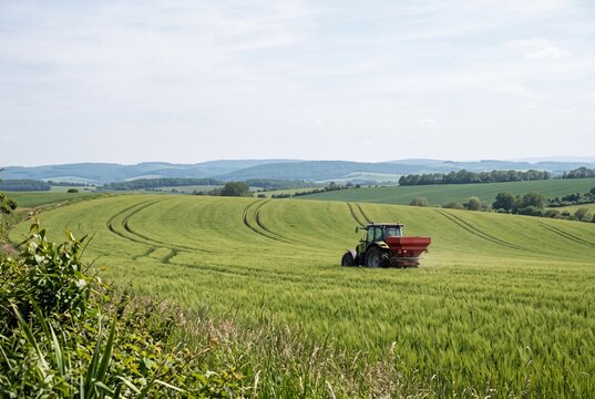 Tractor applying fertilizer to green crop field